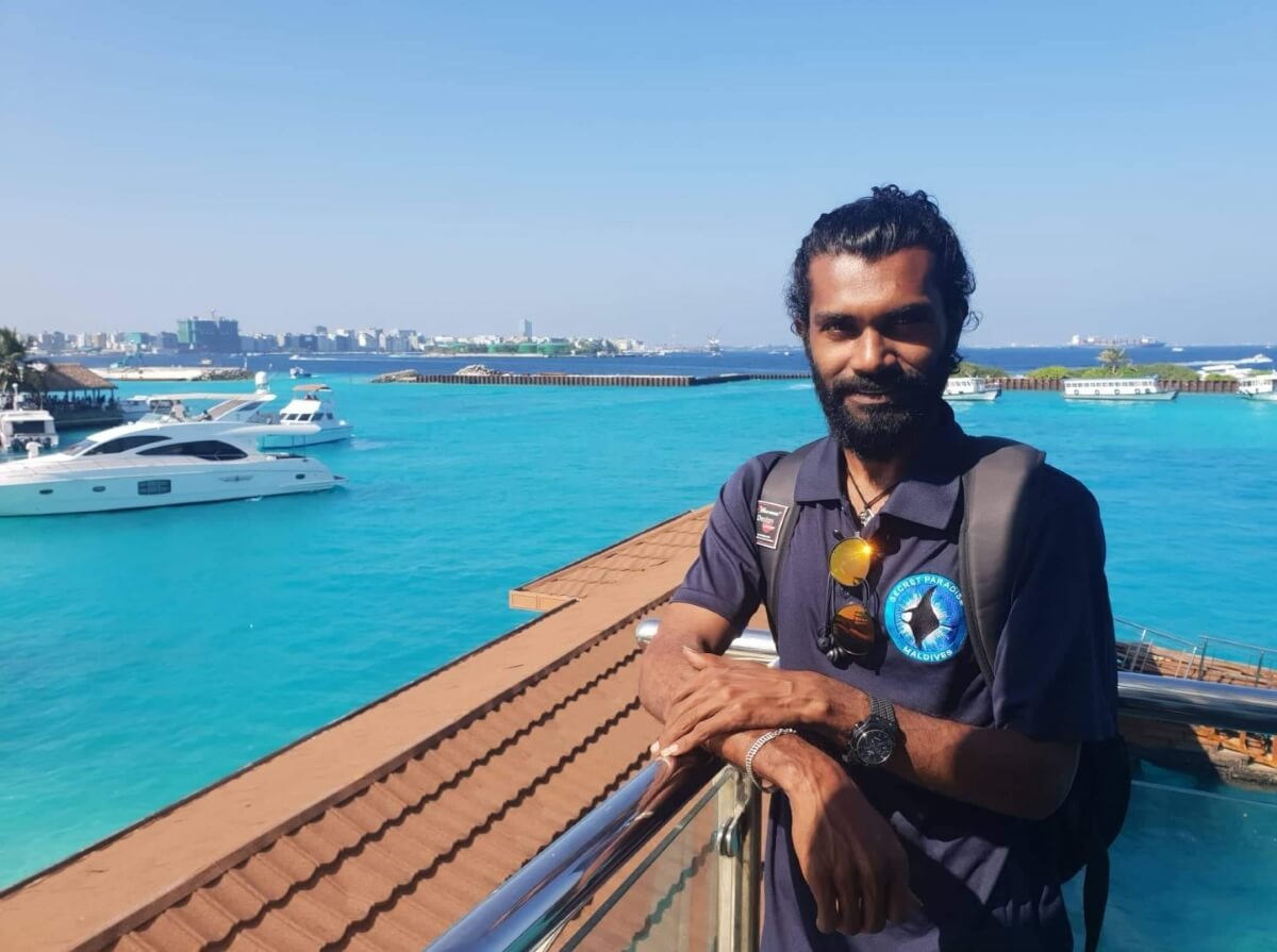 secret paradise staff member stands next to a bay with yachts