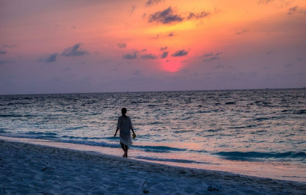Guest-on-an-evening-walk-on-the-beach-in-Maldives-witness-a-colourful-sunset